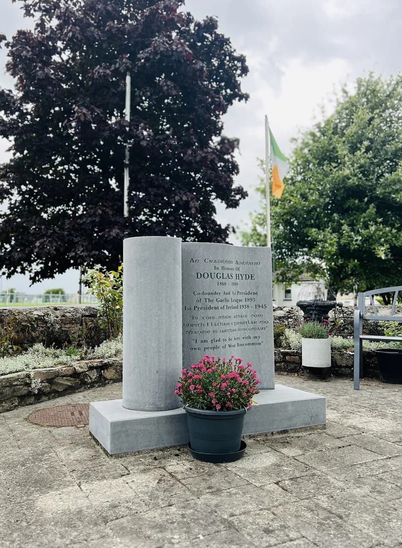 Um alto monumento de pedra a Douglas Hyde erguido na relva em Frenchpark.
