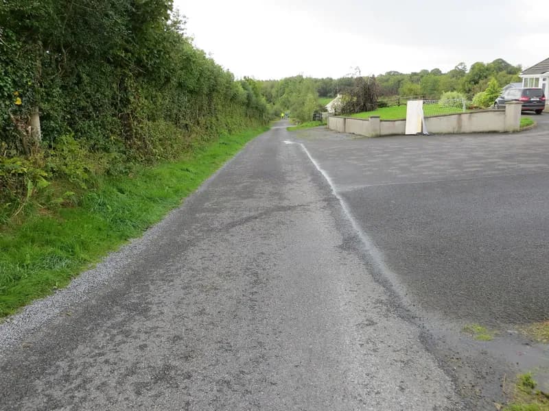 Uma estrada rural estreita entre sebes em direção ao townland de Longford, fora de Castlerea.