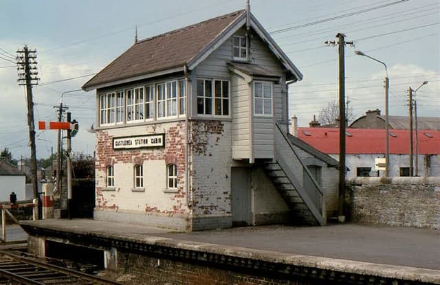 Das Stellwerk am Bahnhof Castlerea: unten Ziegel, oben Holzverschalung und Verglasung, über eine Außentreppe erreichbar.